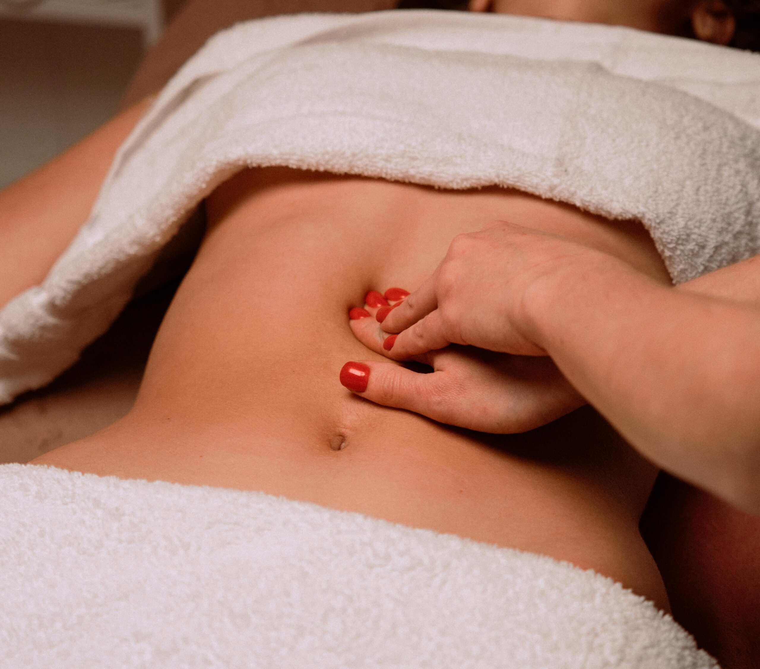 pexels-photo-10894312-10894312 A soothing massage on a woman's abdomen with painted nails, creating a serene spa atmosphere.