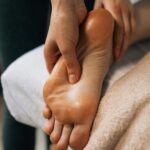 Hands massaging a foot to provide relaxation and promote wellness indoors.